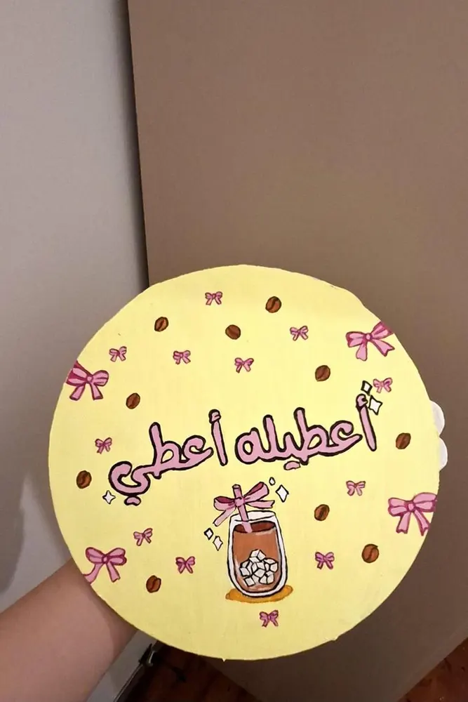 The back of a mirror painted yellow with Arabic lettering and bows