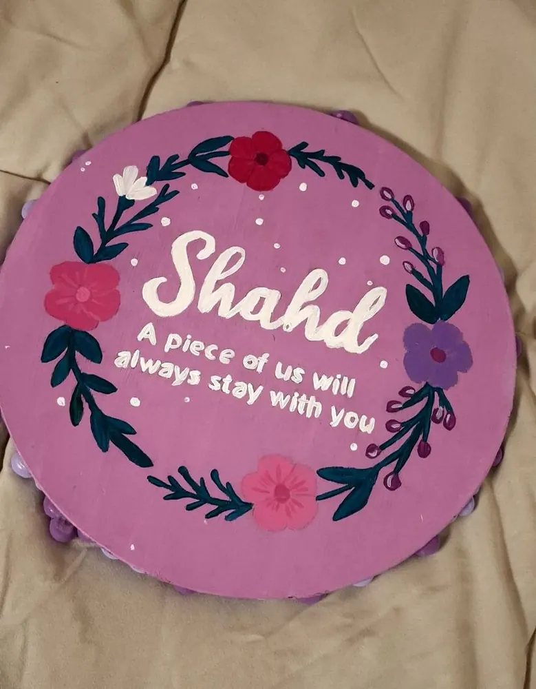 The back of a mirror painted purple with the name Shahd inside a flower wreath